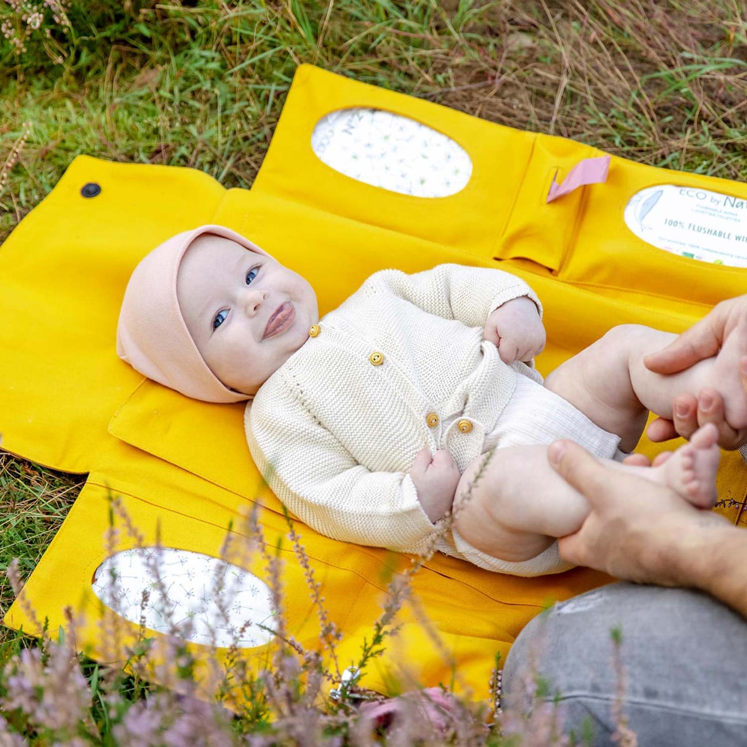 Baby wird auf einer faltbaren Wickelunterlage auf der Wiese bequem gewickelt