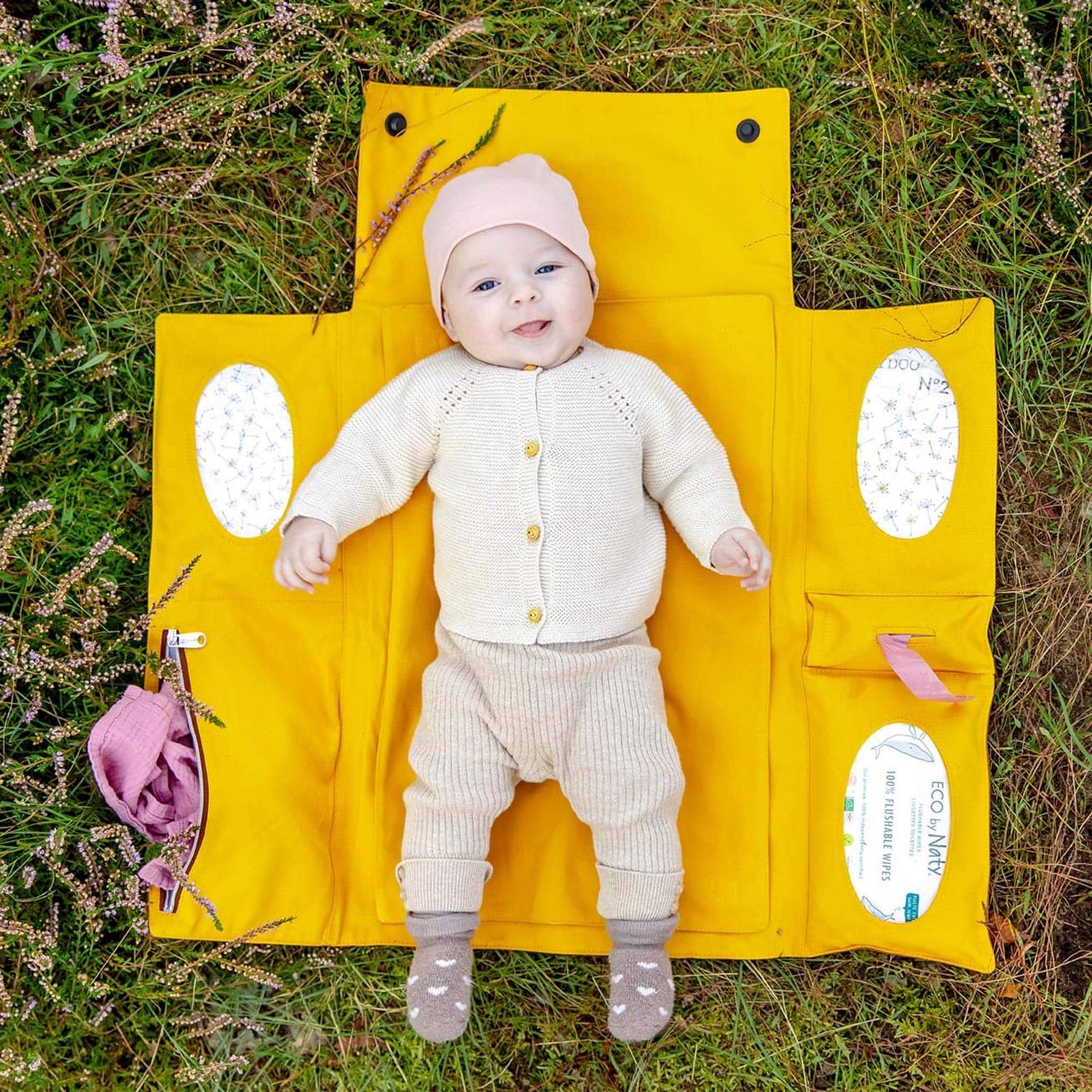 Ein Baby liegt auf der faltbaren Wickeltasche von Villawind auf der Wiese