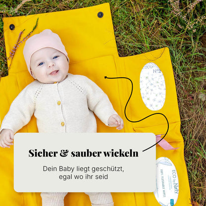 Baby liegt sicher auf Villawind Wickelunterlage im Park auf feuchtem Gras